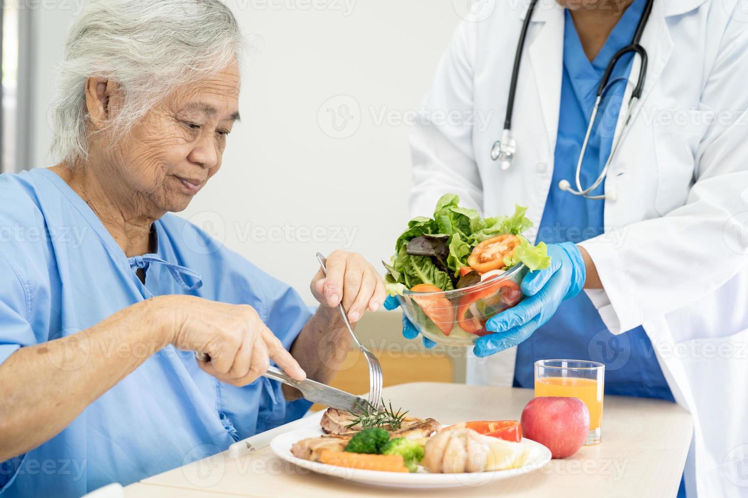 Asian senior or elderly old lady woman patient eating breakfast and vegetable healthy food with hope and happy while sitting and hungry on bed in hospital. photo