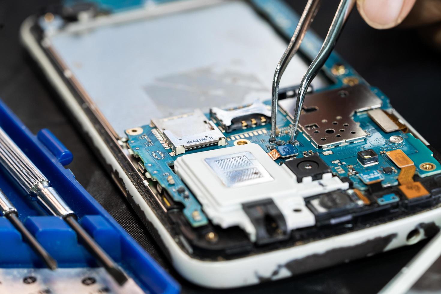 Technician repairing inside of mobile phone by soldering iron. Integrated Circuit. the concept of data, hardware, technology. photo