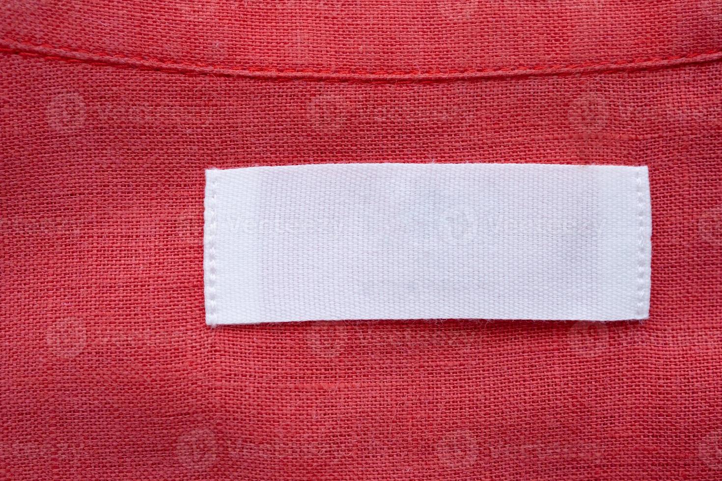 White blank clothing tag label on red linen shirt fabric texture background photo