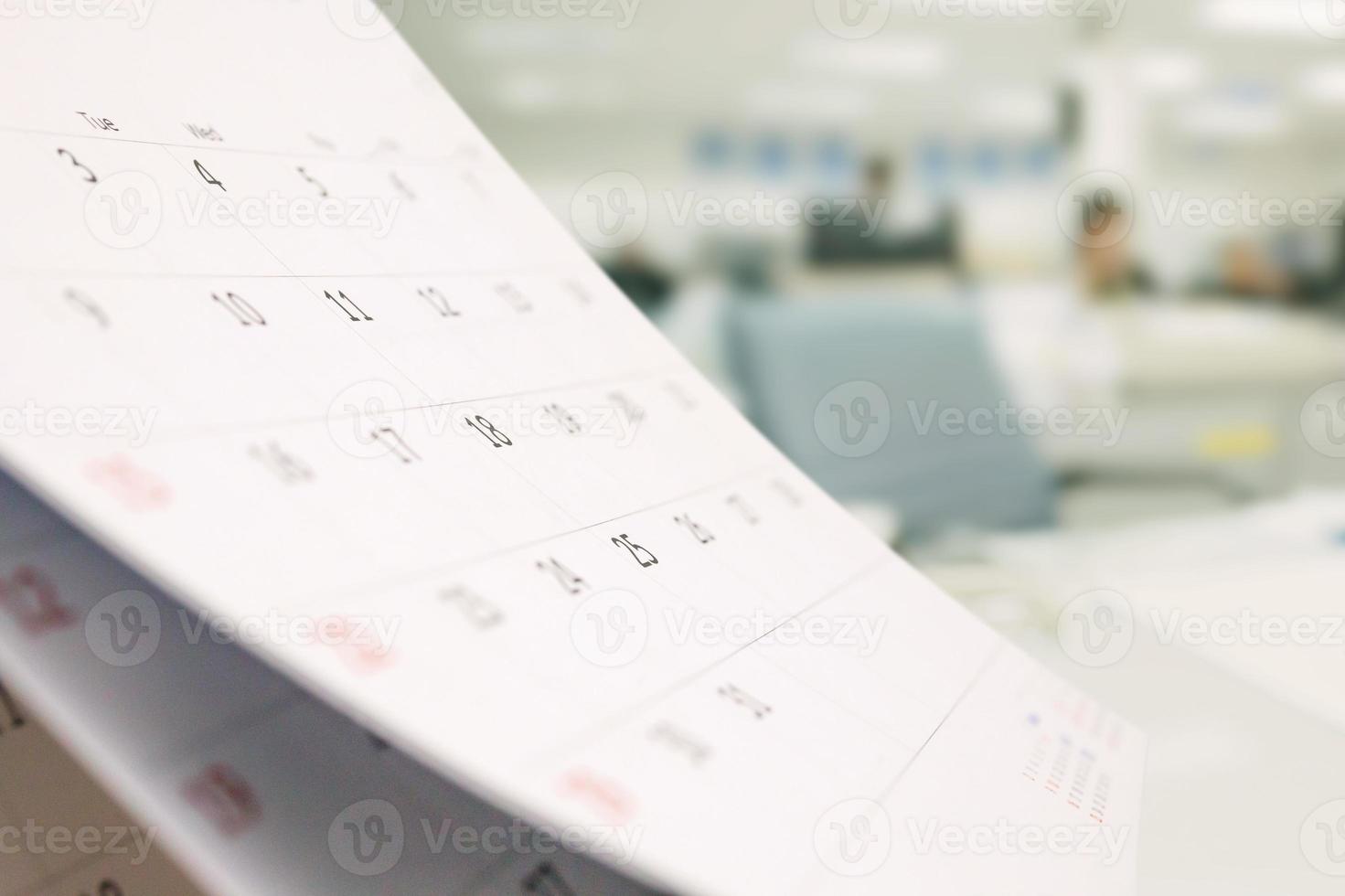 Close up white paper desk calendar on table with blurred office interior background photo