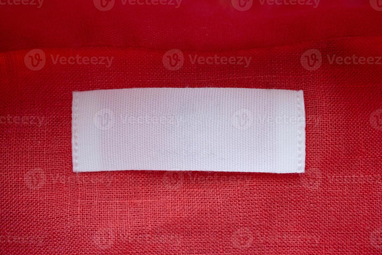 White blank clothing tag label on red linen shirt fabric texture background photo