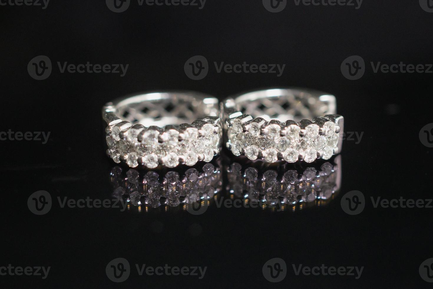 Jewelry diamond earrings on black background with reflection photo