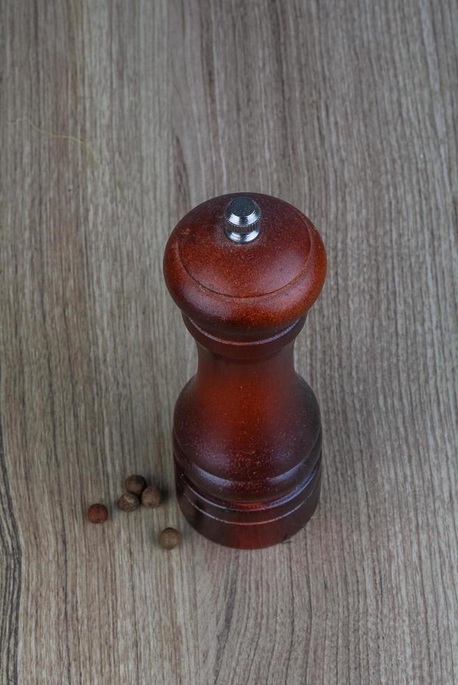 Pepper mill on wooden background photo