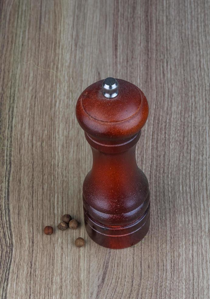 Pepper mill on wooden background photo