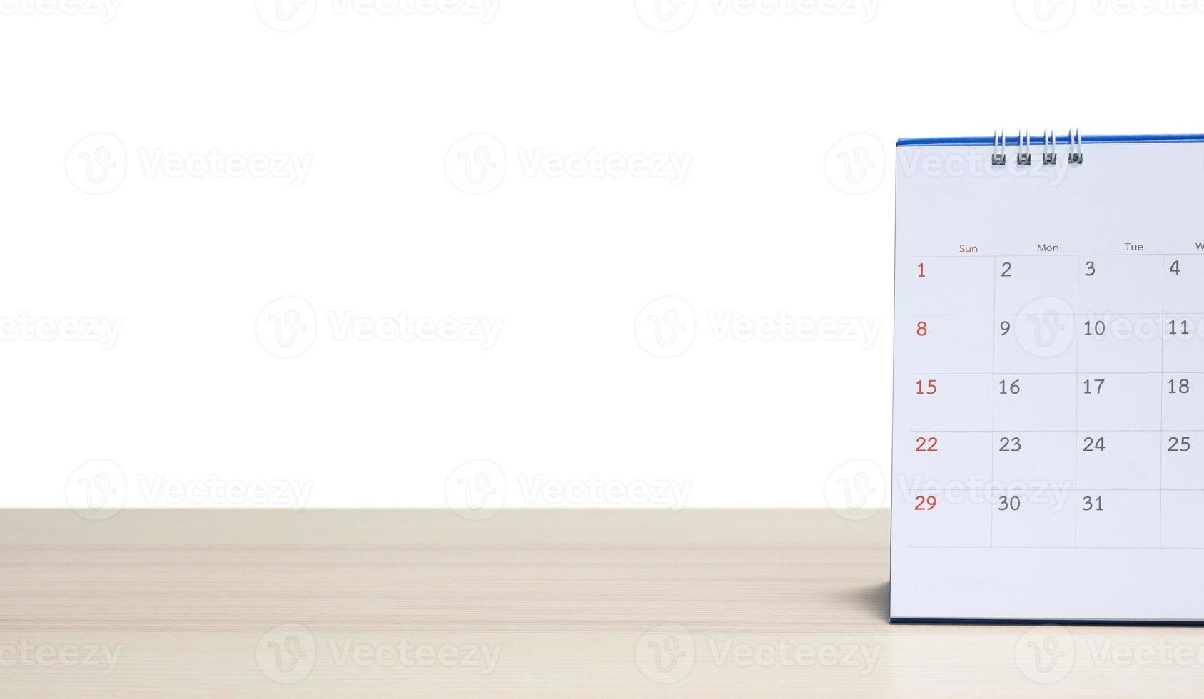 Calendario de escritorio blanco en la parte superior de la mesa de madera aislado sobre fondo blanco. foto