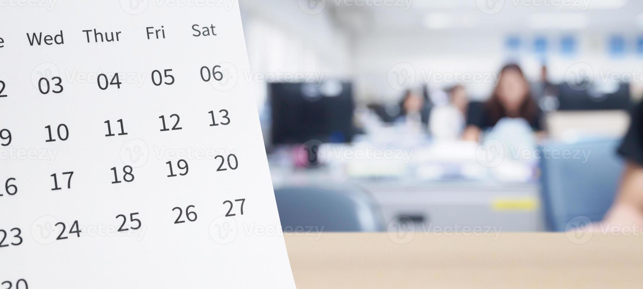calendario de escritorio de papel blanco sobre una mesa de madera con fondo interior de oficina borroso foto