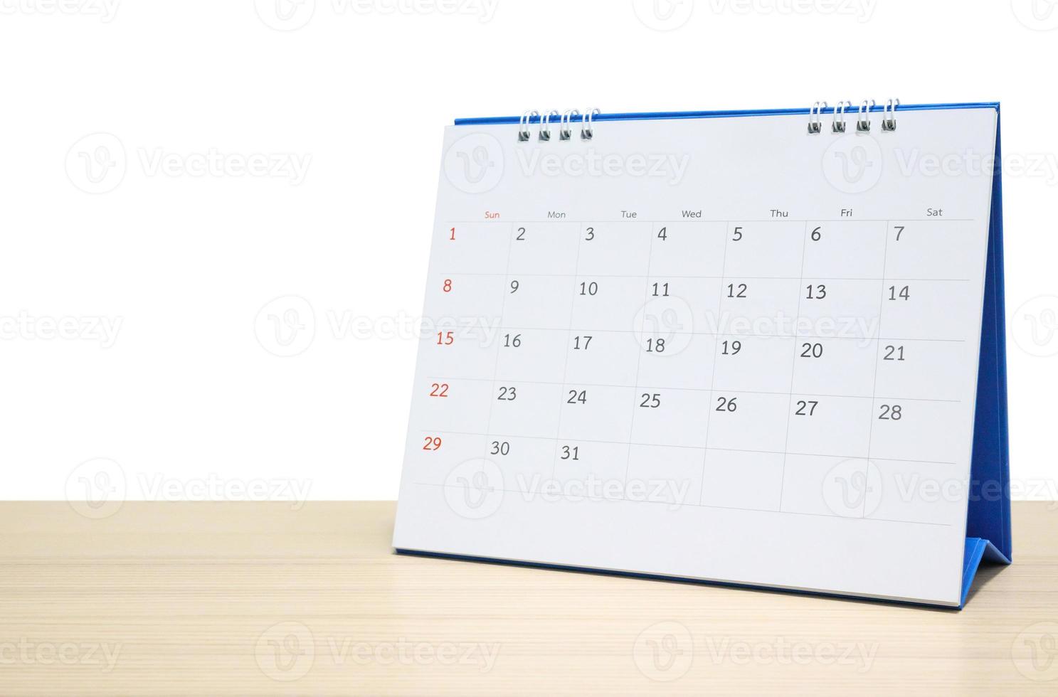 Calendario de escritorio blanco en la parte superior de la mesa de madera aislado sobre fondo blanco. foto