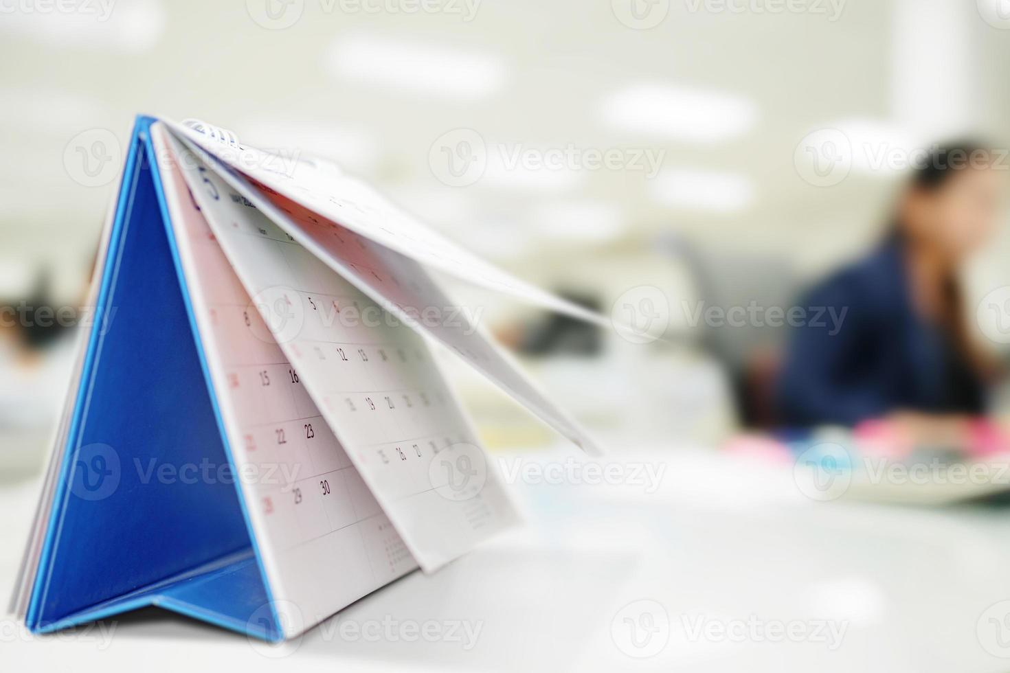 hoja de cambio de página del calendario en la mesa con el fondo interior de la oficina borrosa planificación de la programación de negocios concepto de reunión de cita foto