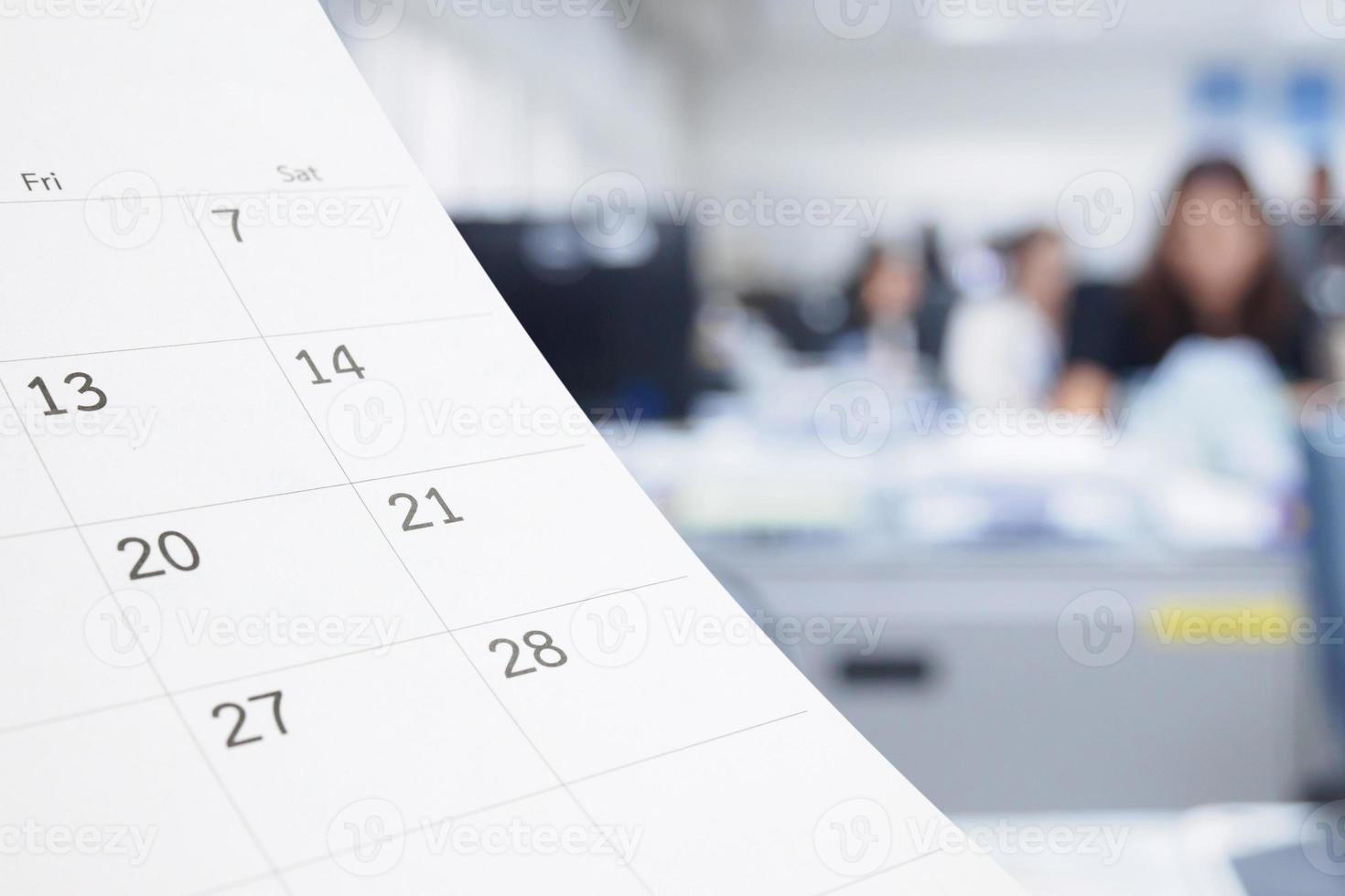 Close up white paper desk calendar on table with blurred office interior background photo