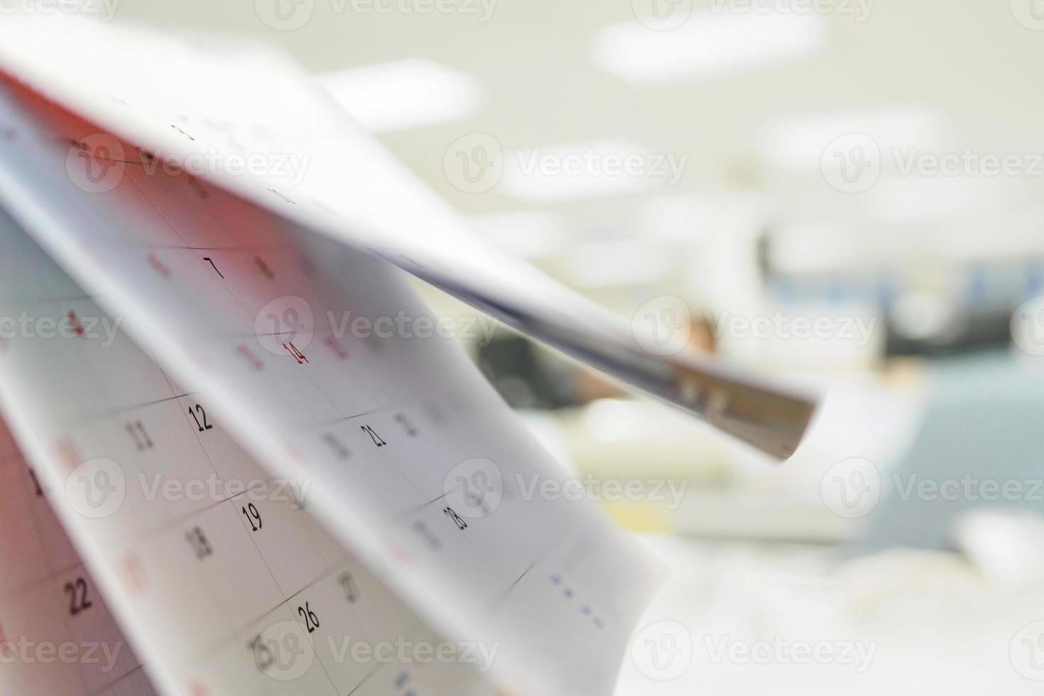Calendar page flipping sheet on table with blurred office interior background business schedule planning appointment meeting concept photo