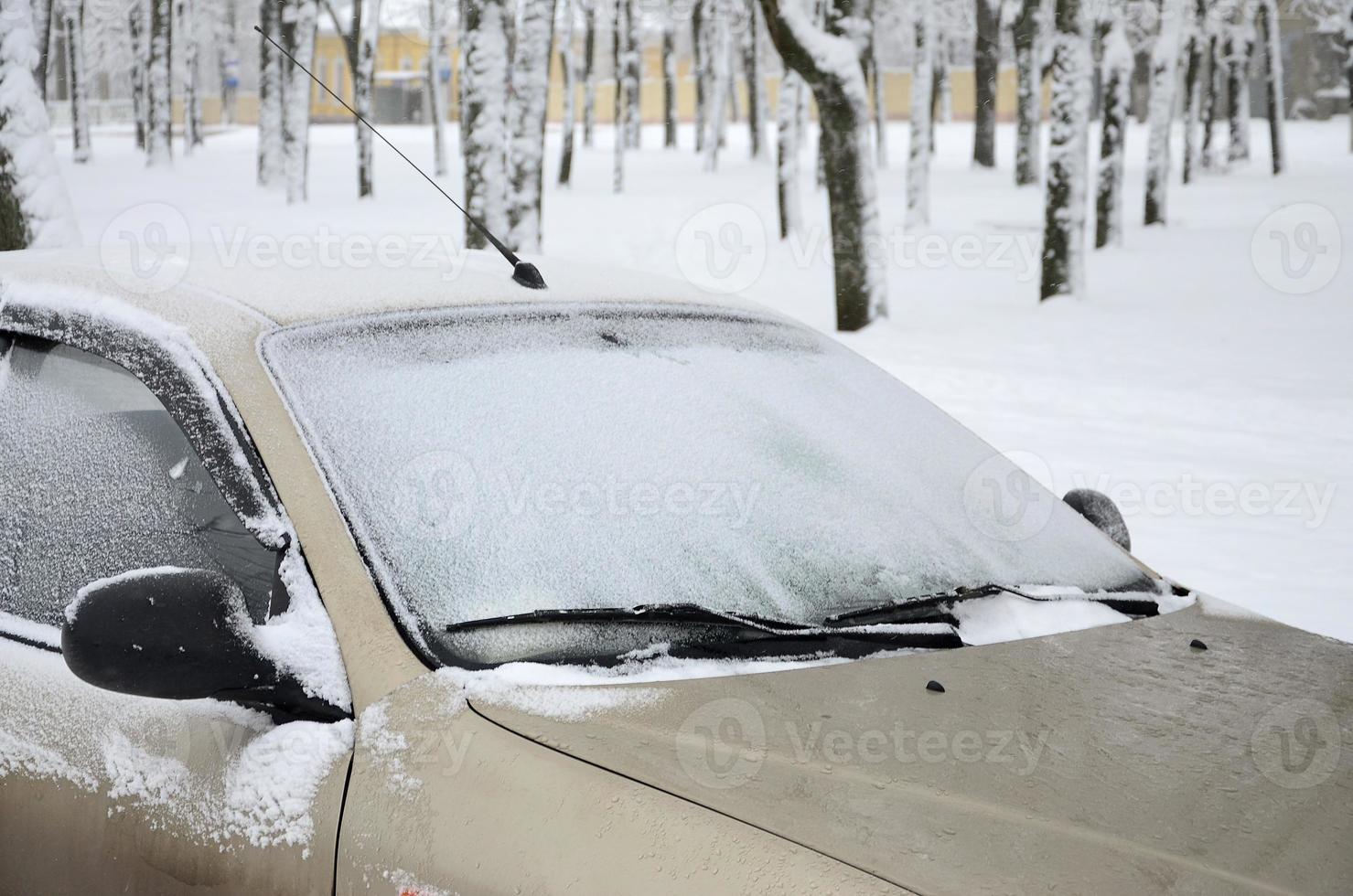 fragmento del coche bajo una capa de nieve después de una fuerte nevada. el cuerpo del coche está cubierto de nieve blanca foto