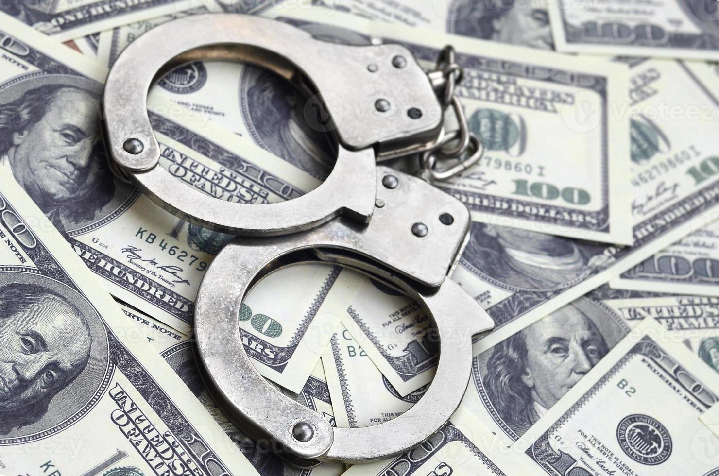 Police handcuffs lie on a lot of dollar bills. The concept of illegal possession of money, illegal transactions with US dollars. Economic Crime photo