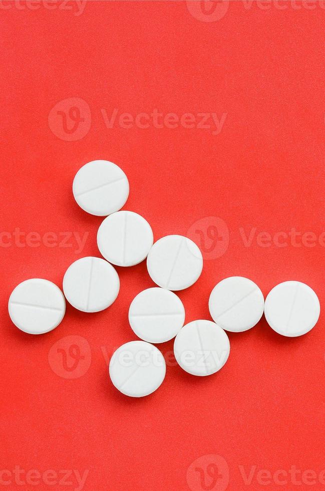 Several white tablets lie on a bright red background in the form of a bacterium. Background image on medicine and pharmaceutical topics photo