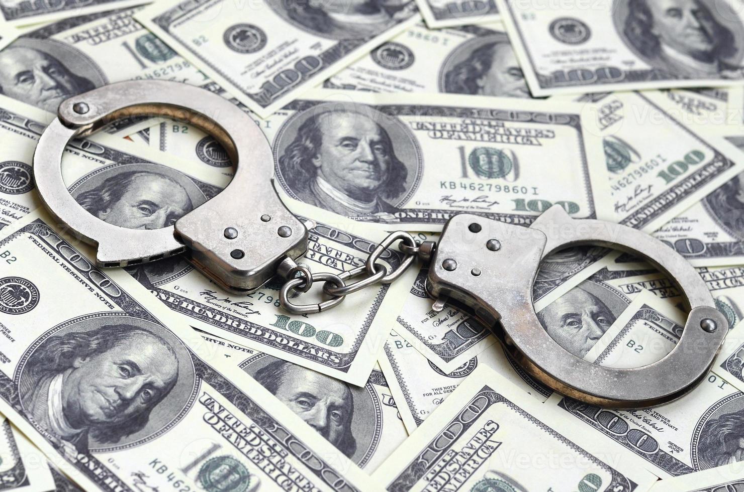 Police handcuffs lie on a lot of dollar bills. The concept of illegal possession of money, illegal transactions with US dollars. Economic Crime photo