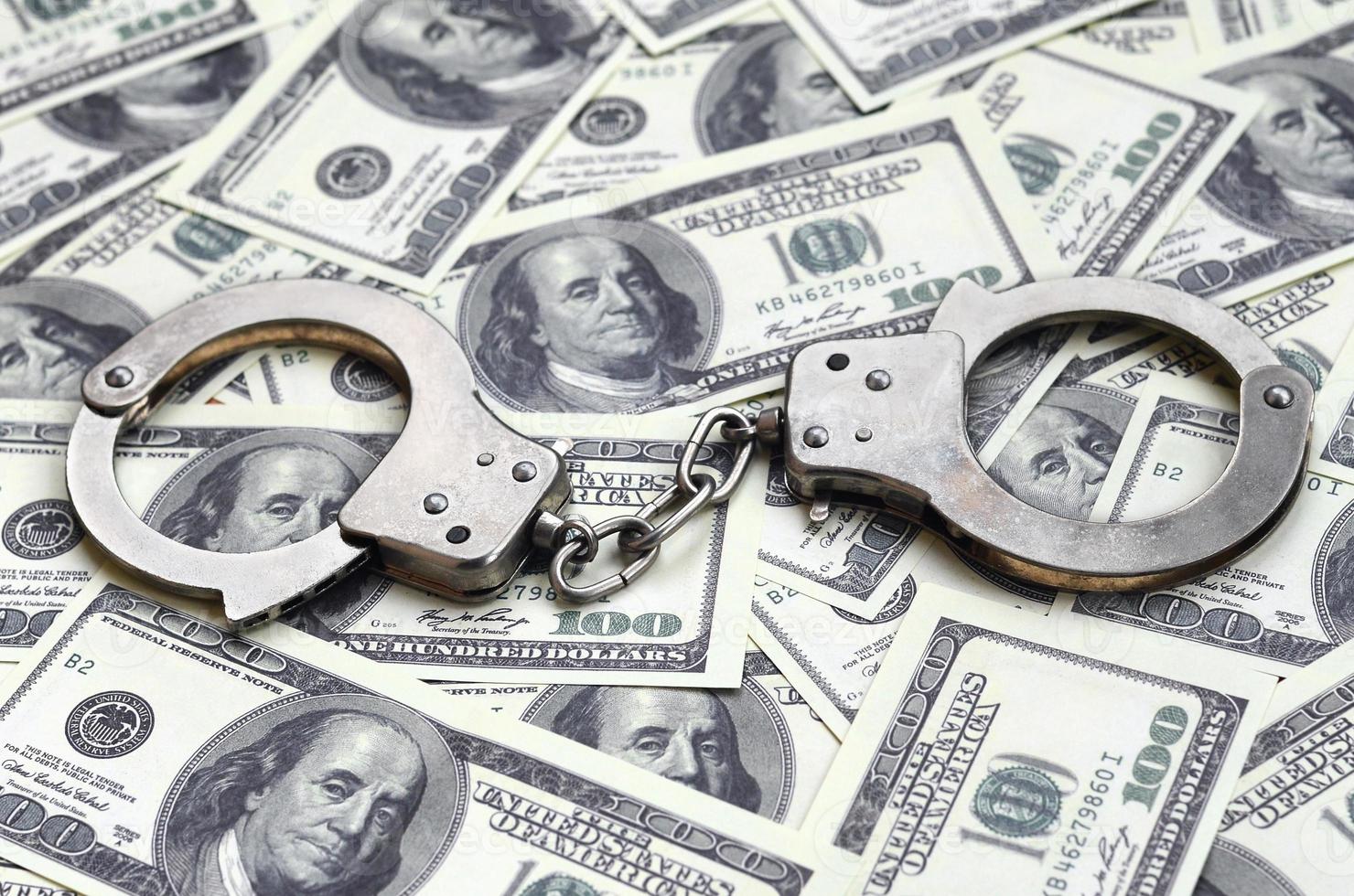 Police handcuffs lie on a lot of dollar bills. The concept of illegal possession of money, illegal transactions with US dollars. Economic Crime photo