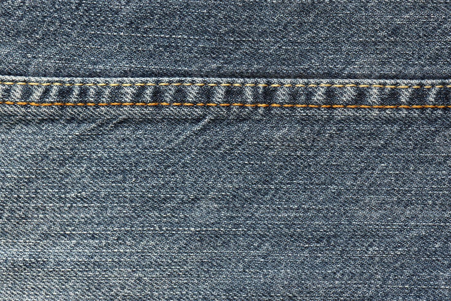 Detailed abstract texture of dark blue denim cloth. Background image of old used denim trousers fabric photo