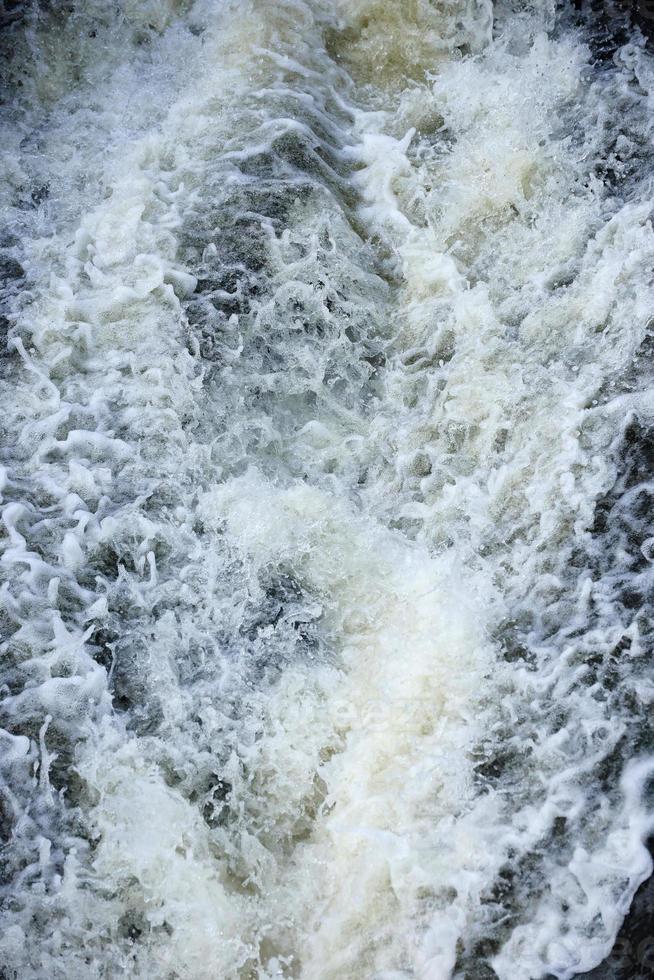 Waves of water of the river and the sea meet each other during high tide and low tide. Deep blue stormy sea water surface with white foam and waves pattern, background photo