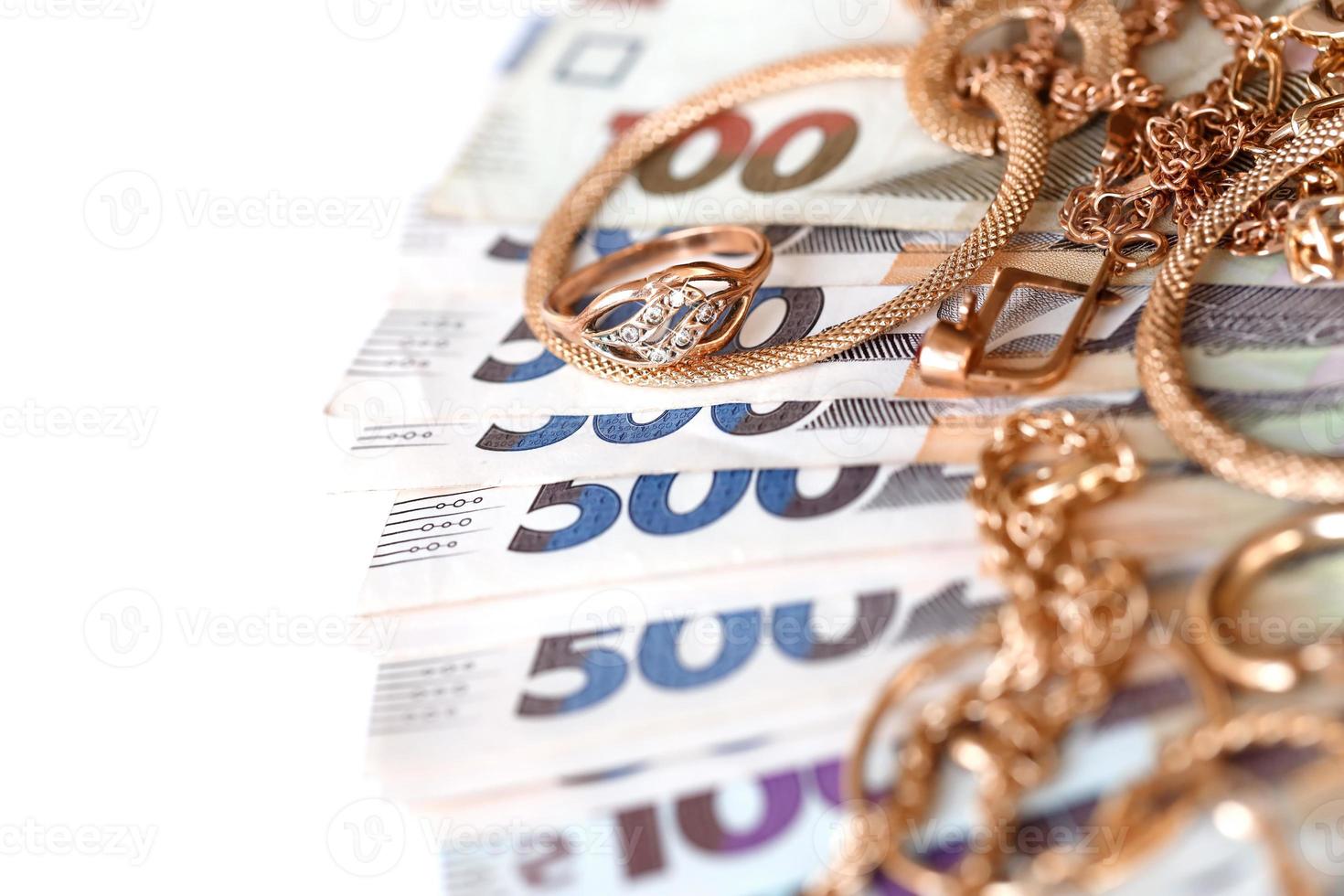 Many expensive golden jewerly rings, earrings and necklaces with big amount of Ukrainian money bills. Pawnshop or jewerly shop concept. Jewelry trading photo