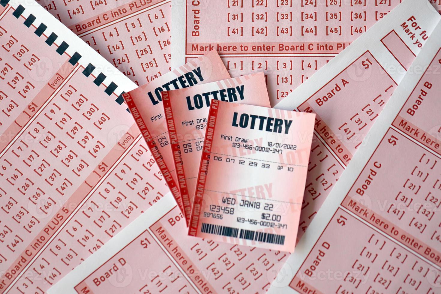 Red lottery ticket lies on pink gambling sheets with numbers for marking to play lottery. Lottery playing concept or gambling addiction. Close up photo