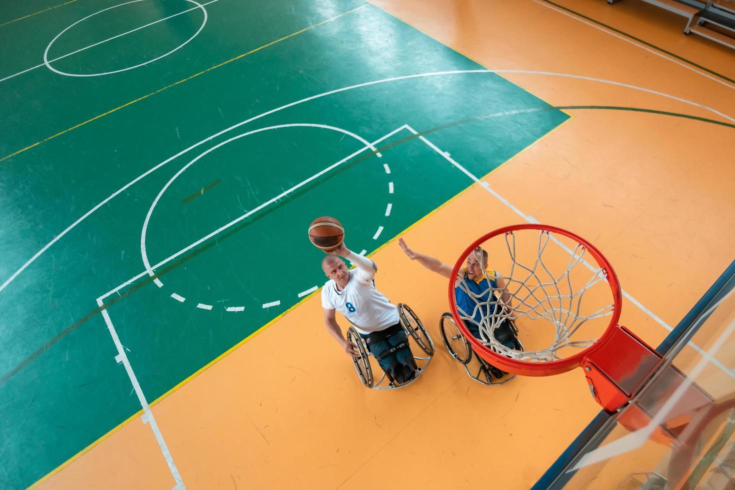 veteranos de guerra o de trabajo discapacitados equipos mixtos de baloncesto de raza y edad en sillas de ruedas jugando un partido de entrenamiento en un gimnasio deportivo. concepto de rehabilitación e inclusión de personas con discapacidad. foto