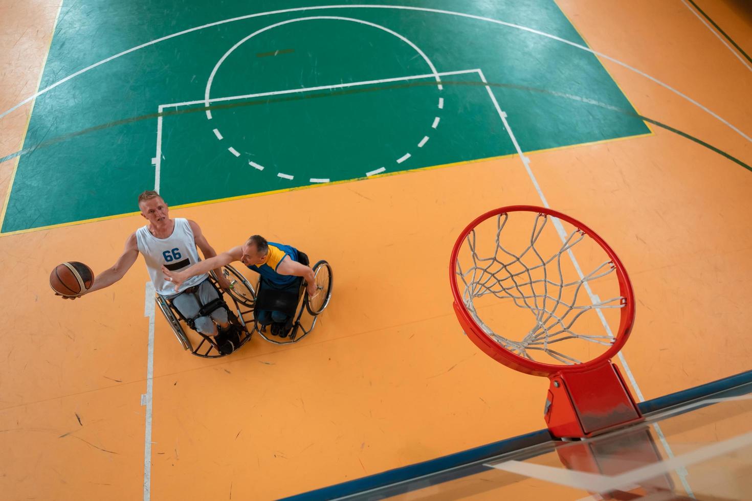 veteranos de guerra o de trabajo discapacitados equipos mixtos de baloncesto de raza y edad en sillas de ruedas jugando un partido de entrenamiento en un gimnasio deportivo. concepto de rehabilitación e inclusión de personas con discapacidad. foto