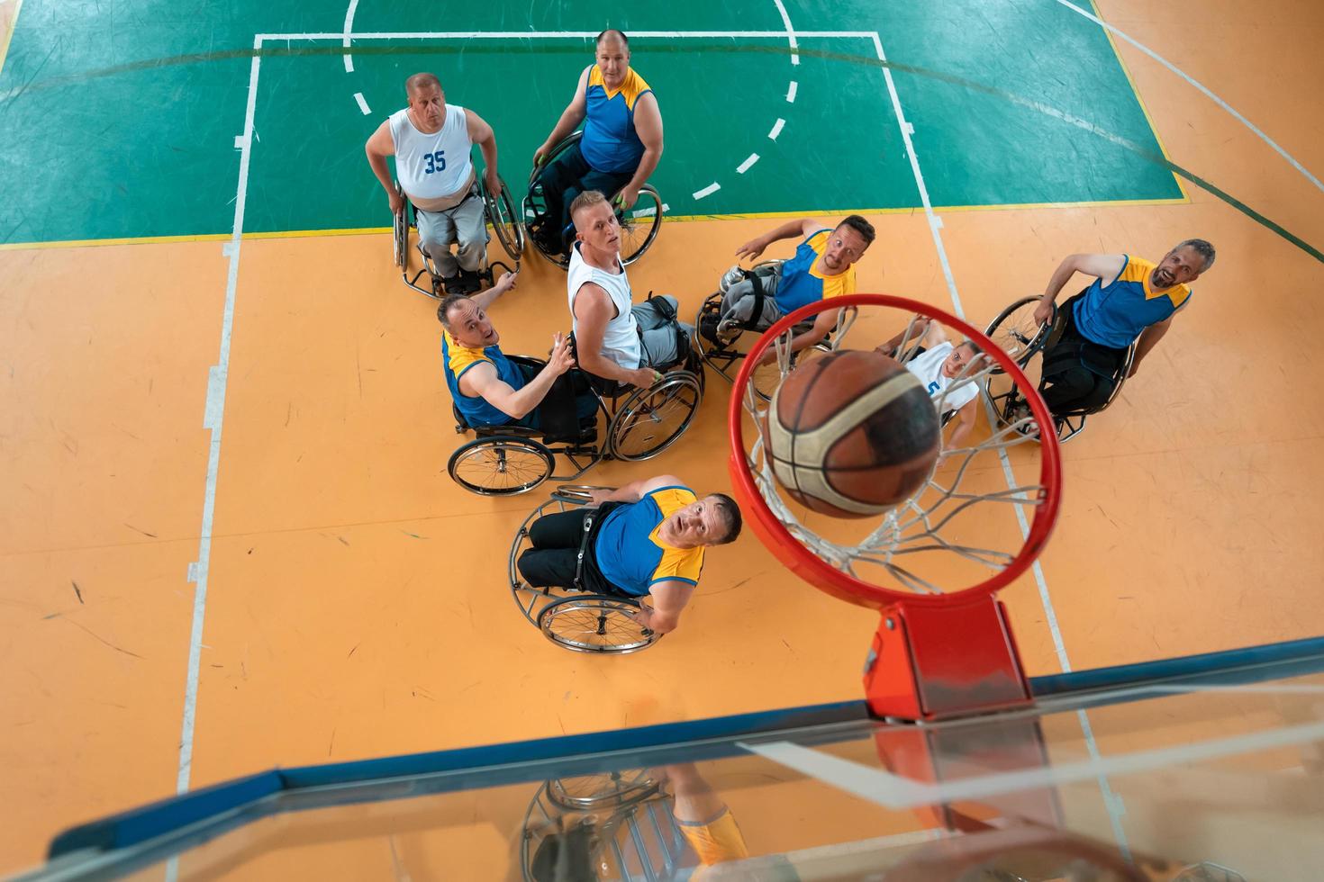 Disabled War or work veterans mixed race and age basketball teams in wheelchairs playing a training match in a sports gym hall. Handicapped people rehabilitation and inclusion concept. photo