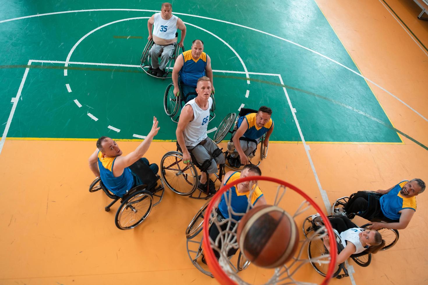 Disabled War or work veterans mixed race and age basketball teams in wheelchairs playing a training match in a sports gym hall. Handicapped people rehabilitation and inclusion concept. photo