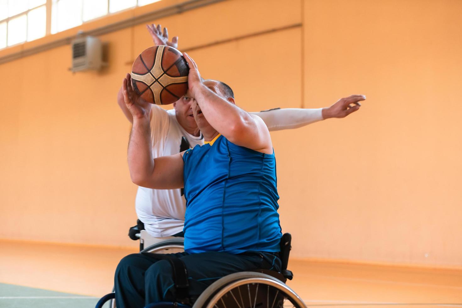 Disabled War veterans mixed race and age basketball teams in wheelchairs playing a training match in a sports gym hall. Handicapped people rehabilitation and inclusion concept photo