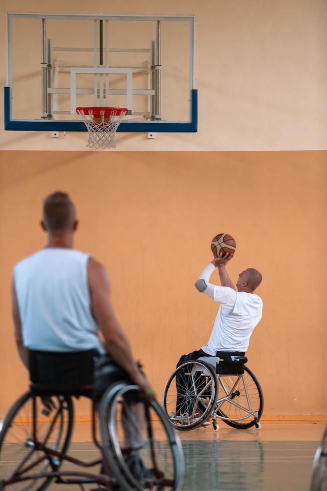 Disabled War veterans mixed race and age basketball teams in wheelchairs playing a training match in a sports gym hall. Handicapped people rehabilitation and inclusion concept photo