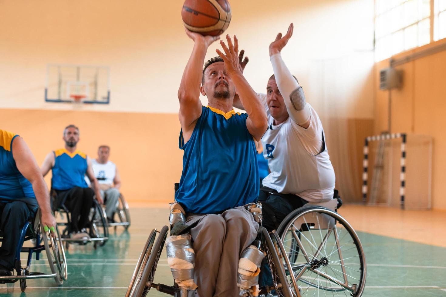 Disabled War veterans mixed race and age basketball teams in wheelchairs playing a training match in a sports gym hall. Handicapped people rehabilitation and inclusion concept photo