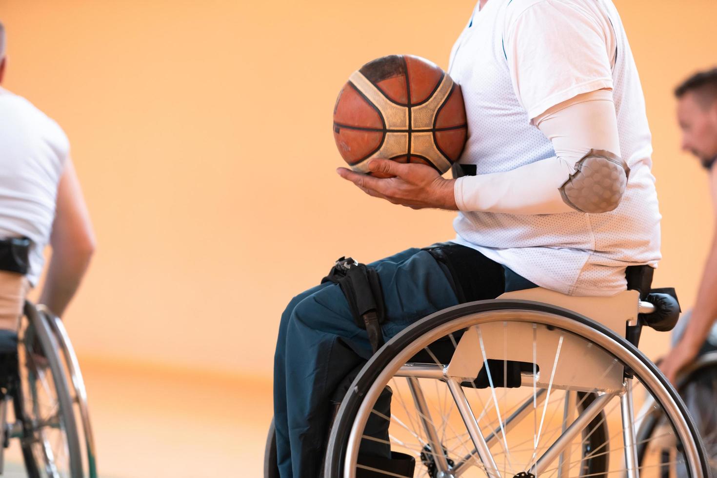 Close up photo of wheelchairs and handicapped war veterans playing basketball on the court