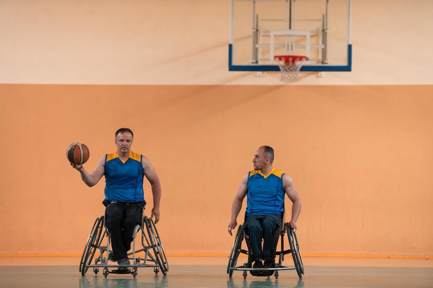 Disabled War veterans mixed race and age basketball teams in wheelchairs playing a training match in a sports gym hall. Handicapped people rehabilitation and inclusion concept photo