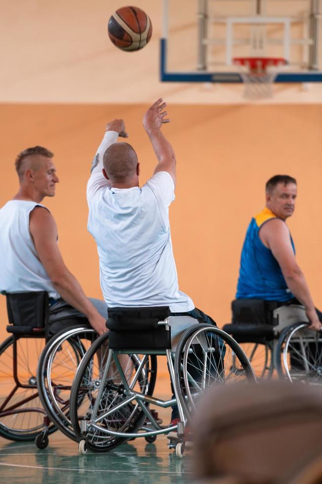 Disabled War veterans mixed race and age basketball teams in wheelchairs playing a training match in a sports gym hall. Handicapped people rehabilitation and inclusion concept photo