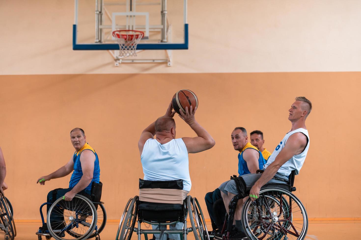 Disabled War veterans mixed race and age basketball teams in wheelchairs playing a training match in a sports gym hall. Handicapped people rehabilitation and inclusion concept photo