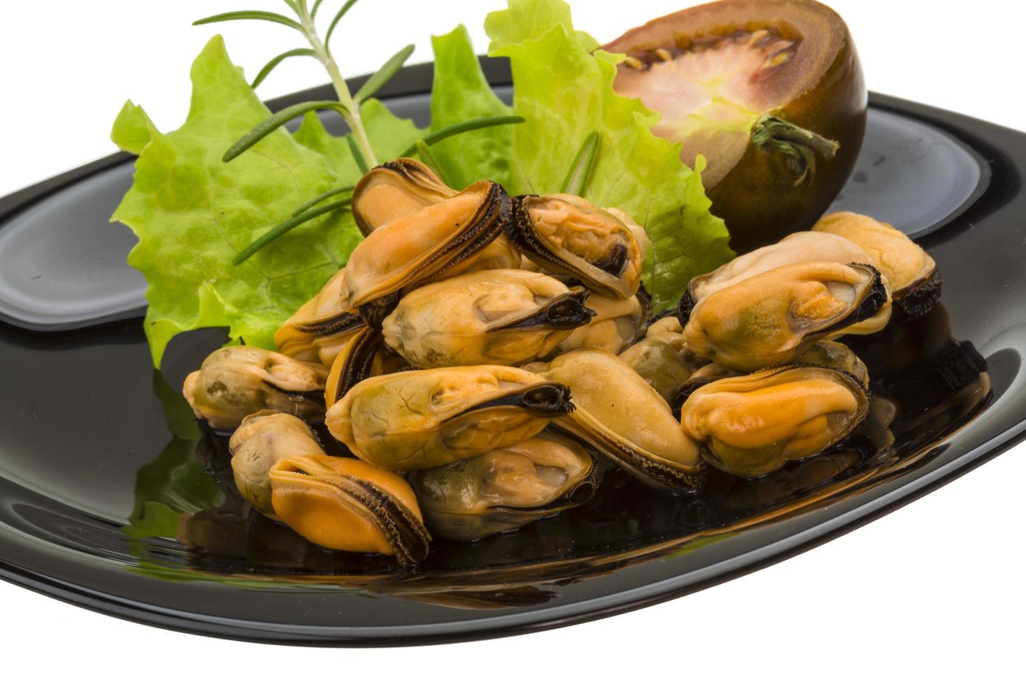 mejillones marinados en el plato y fondo blanco foto