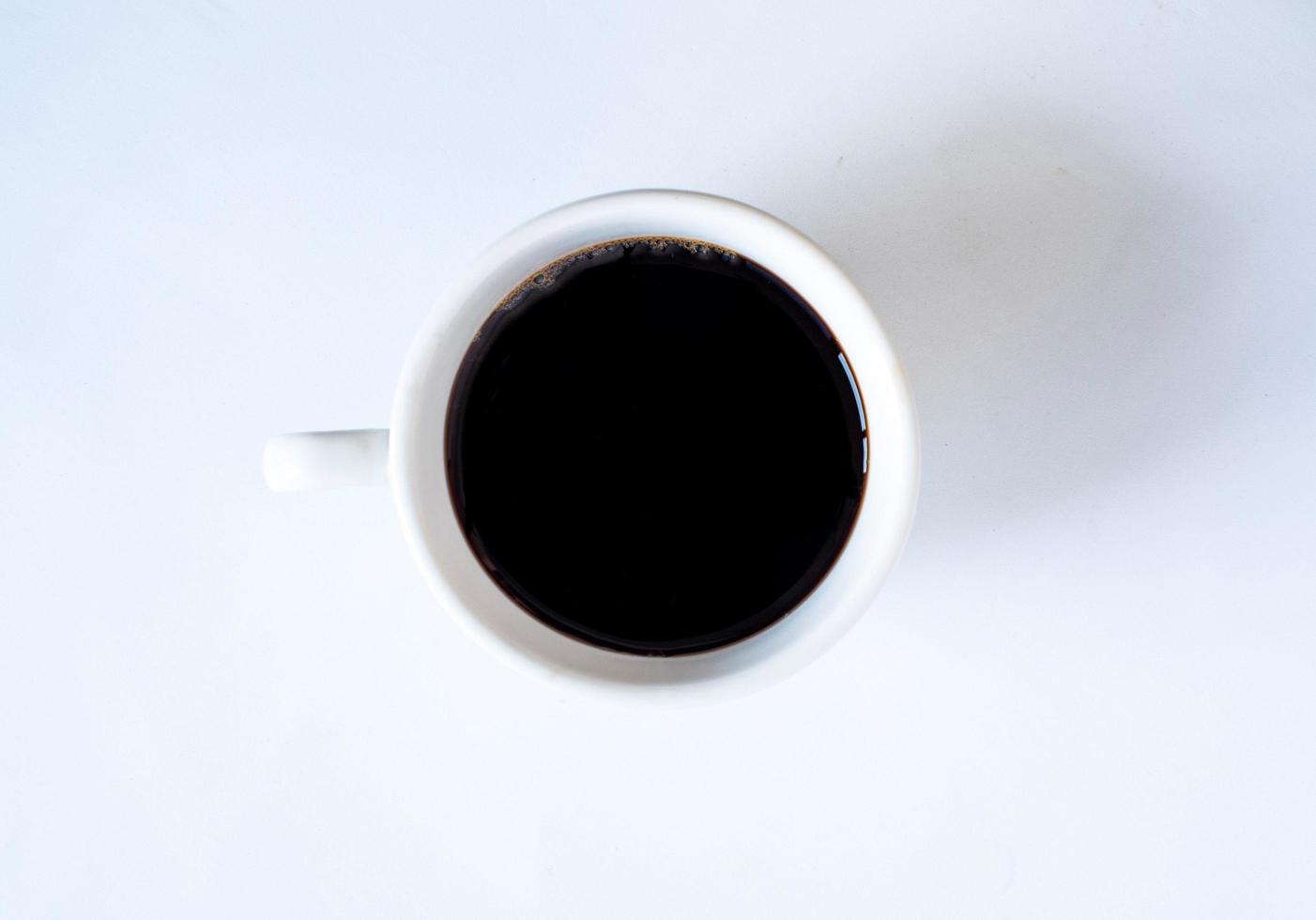 fotografía de la vista superior de la taza de café con leche en un plato blanco el interior del vaso parece vacío. esperando que se rellene el café caliente para beber para sentirse renovado y alerta sobre un fondo blanco. foto
