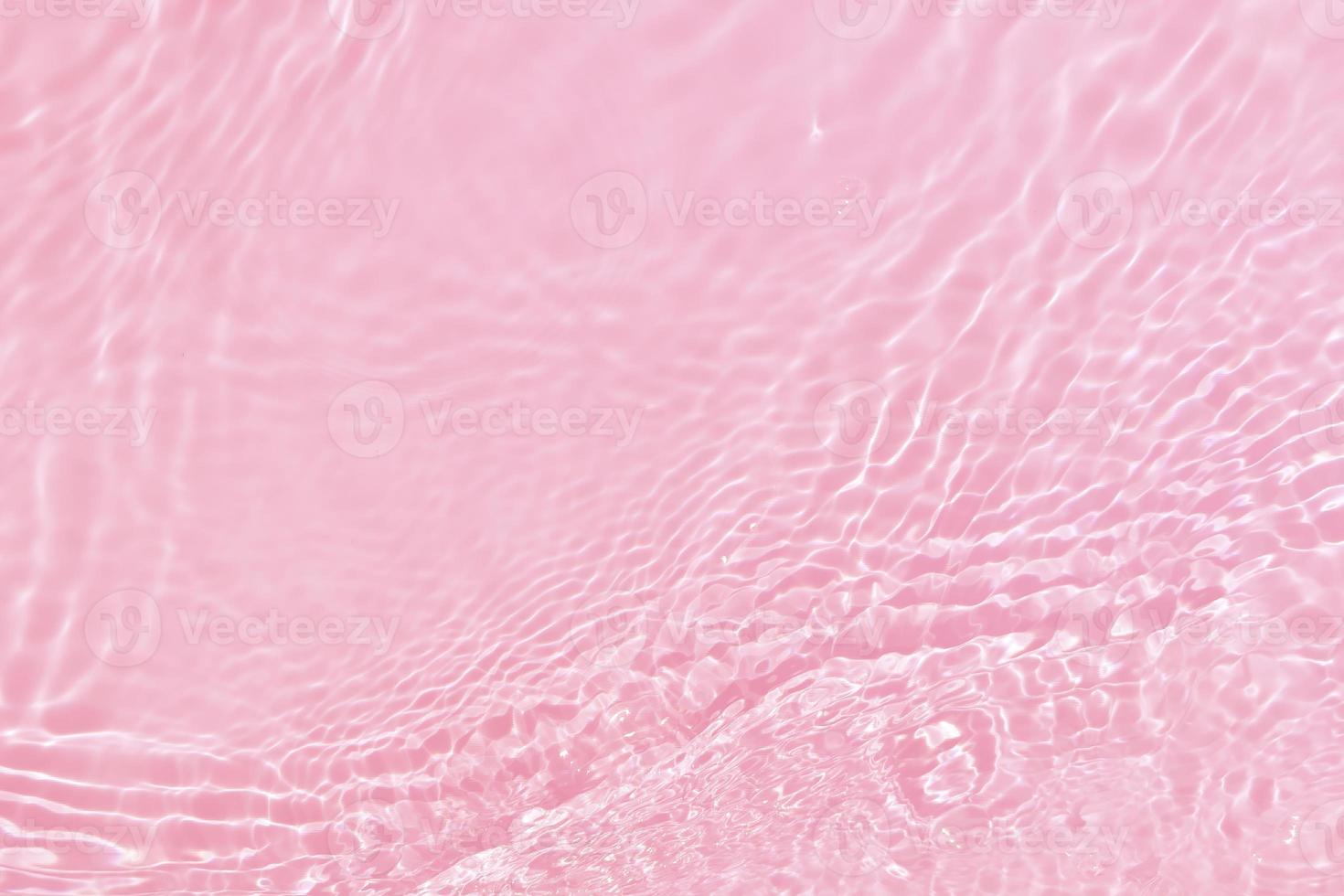 desenfoque borroso transparente color rosa claro agua tranquila textura superficial con salpicaduras, burbujas. fondo de ondulación de agua rosa brillante. superficie del agua en la piscina. agua de burbujas rosadas que brilla. foto