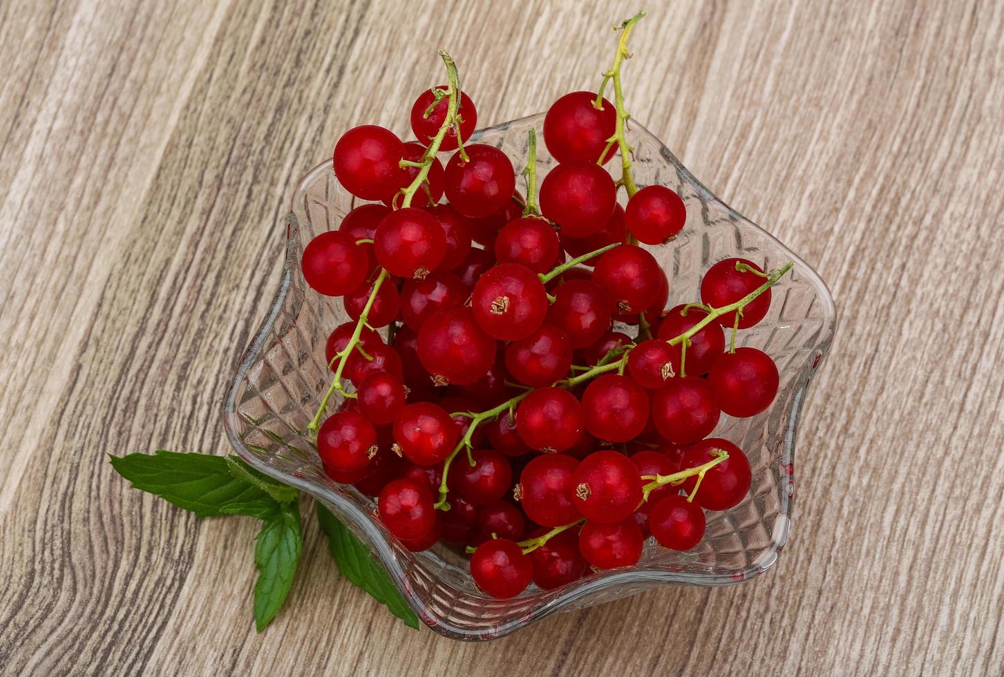 Red currant in a bowl on wooden background photo