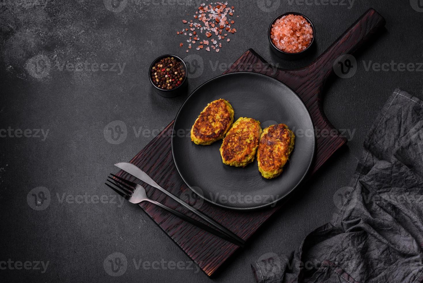 Diet vegetable cutlet from zucchini, carrot, herbs on a black plate photo