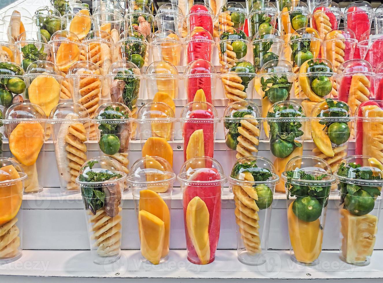 Mix fruits in a plastic glass on wooden shelves photo