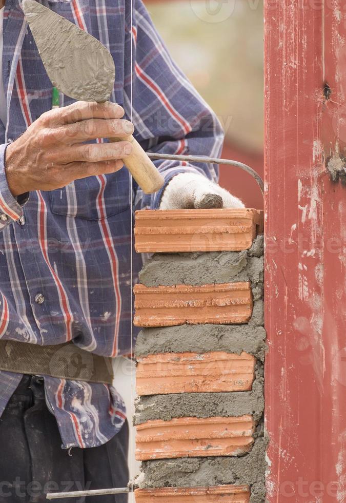 Bricklayer working in construction site of  brick wall photo