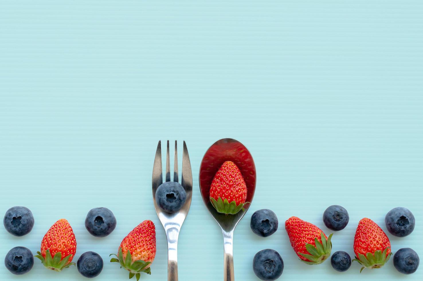 The fork and spoon with strawberry and blueberry fruits. photo