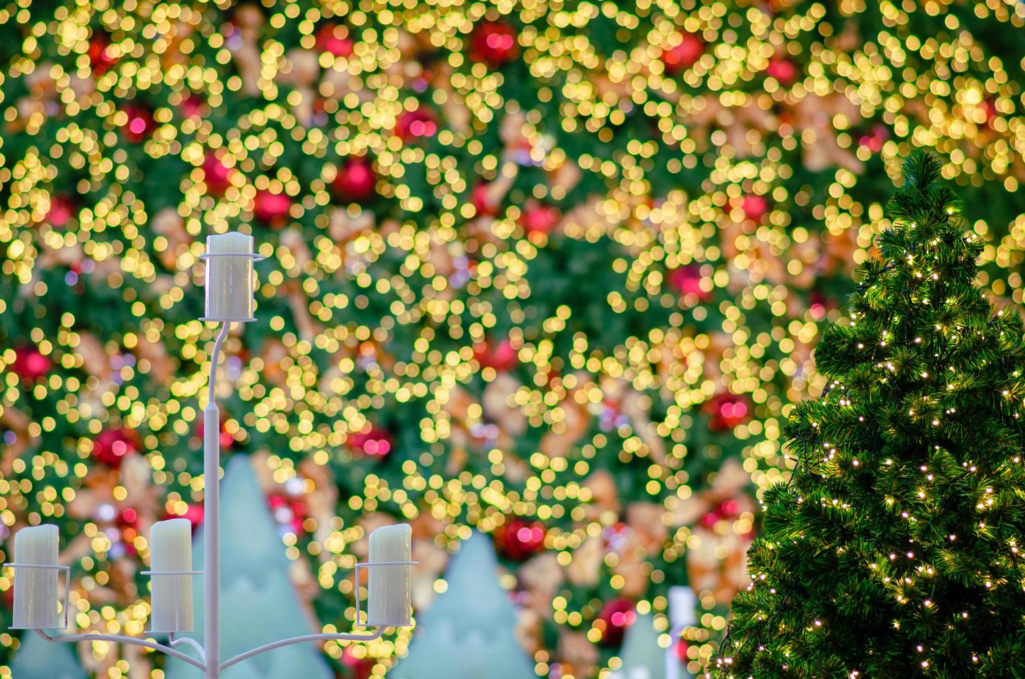 pequeño árbol de navidad con fondo de luces bokeh de otro grande para el festival navideño. foto