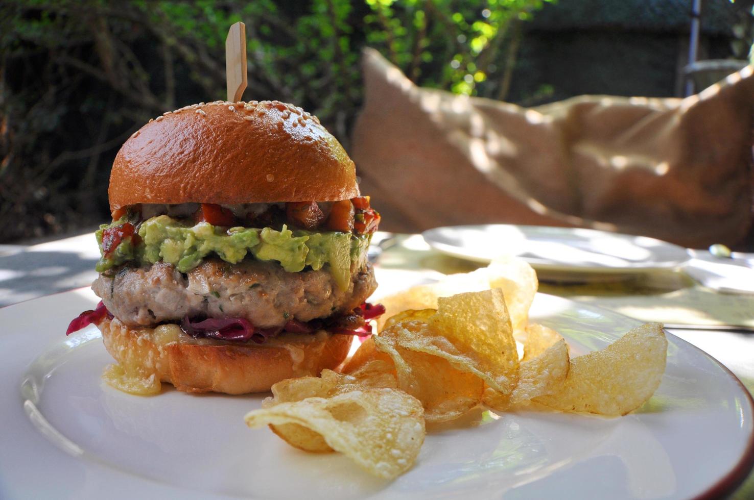 Fresh Burger with meat, tomato, avocado, cheese, red cabbage, pickle and chips. photo