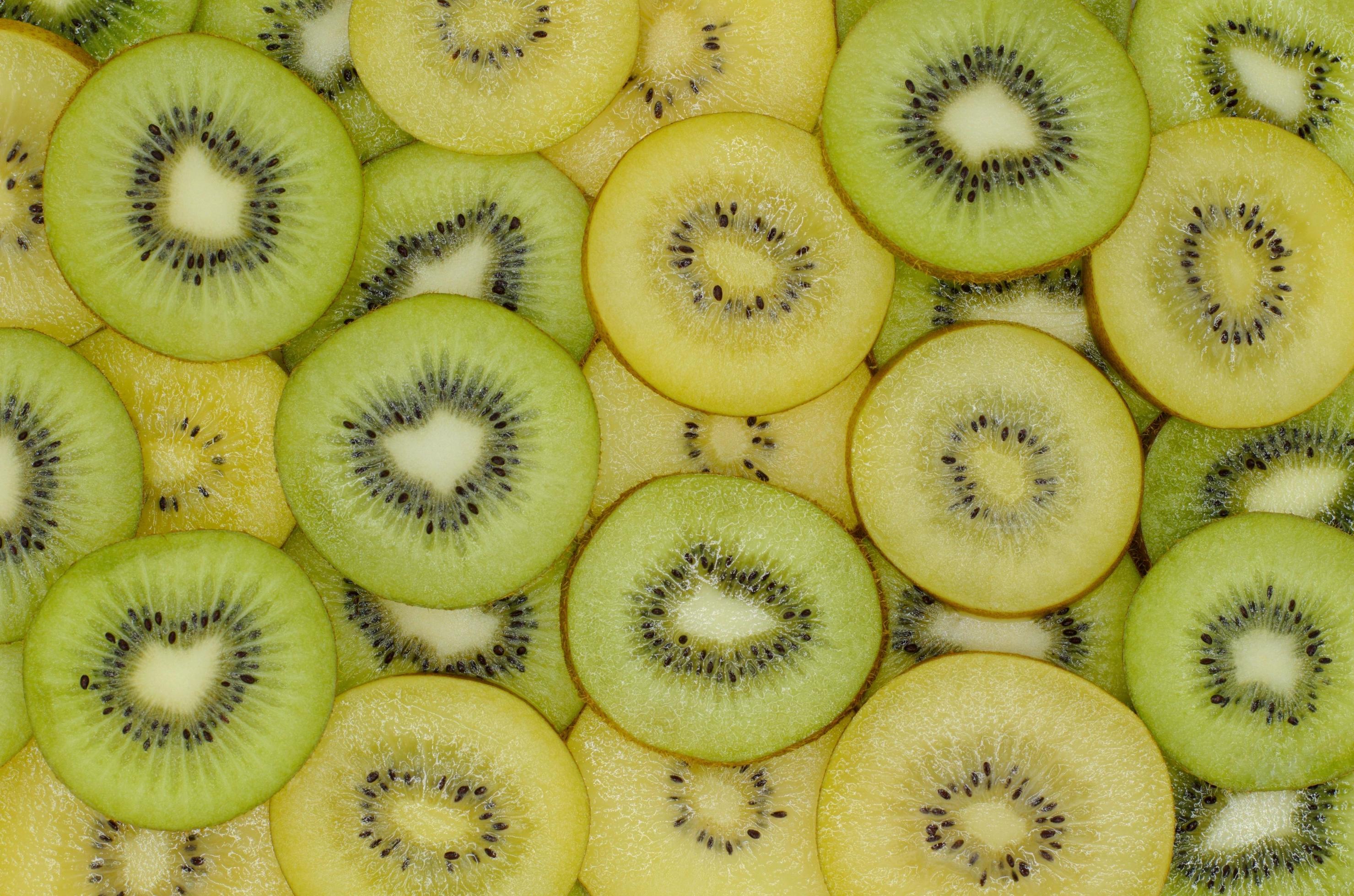 Slices of fresh green and yellow kiwi fruits set as background from top