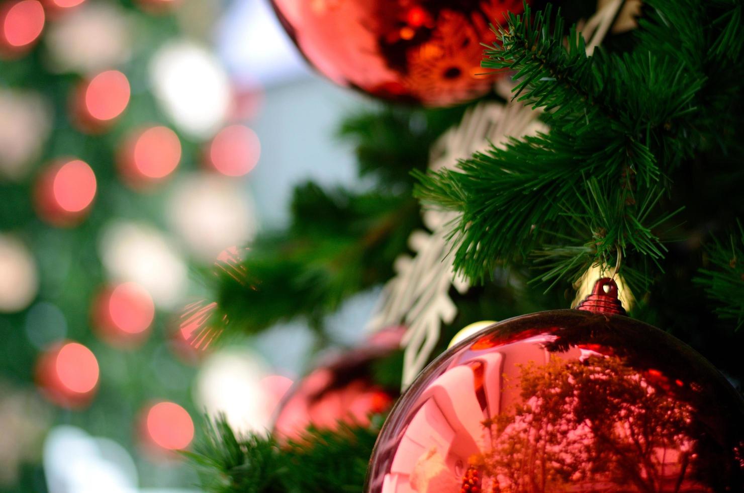 decoración de adorno rojo en el árbol de navidad con fondo bokeh de otro árbol de navidad. foto