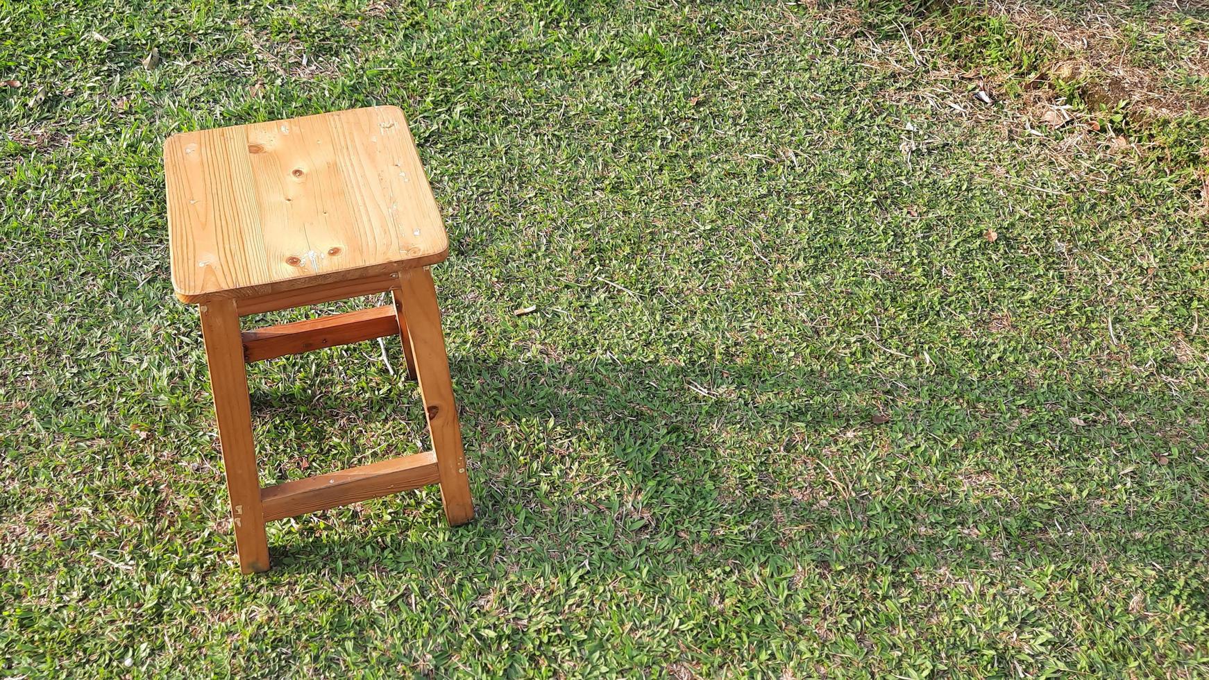 Brown wooden chair on green grass with shadow in the sun photo