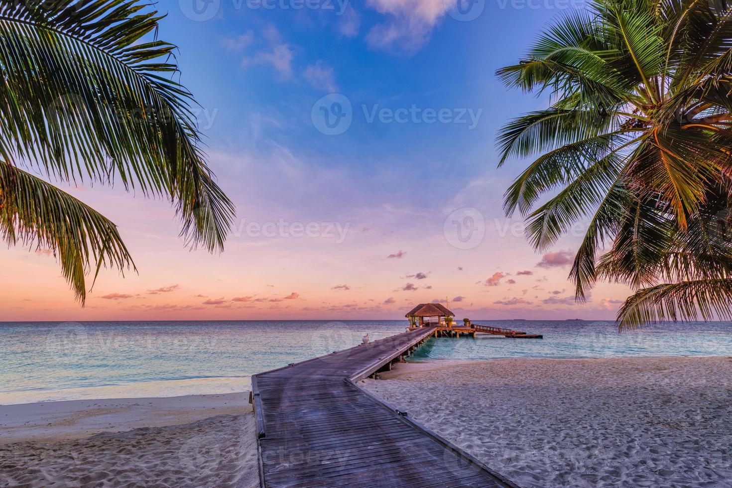 Amazing sunset panorama at Maldives. Luxury resort villas seascape with soft led lights under colorful sky. Beautiful twilight sky and colorful clouds. Beautiful beach background for vacation holiday photo