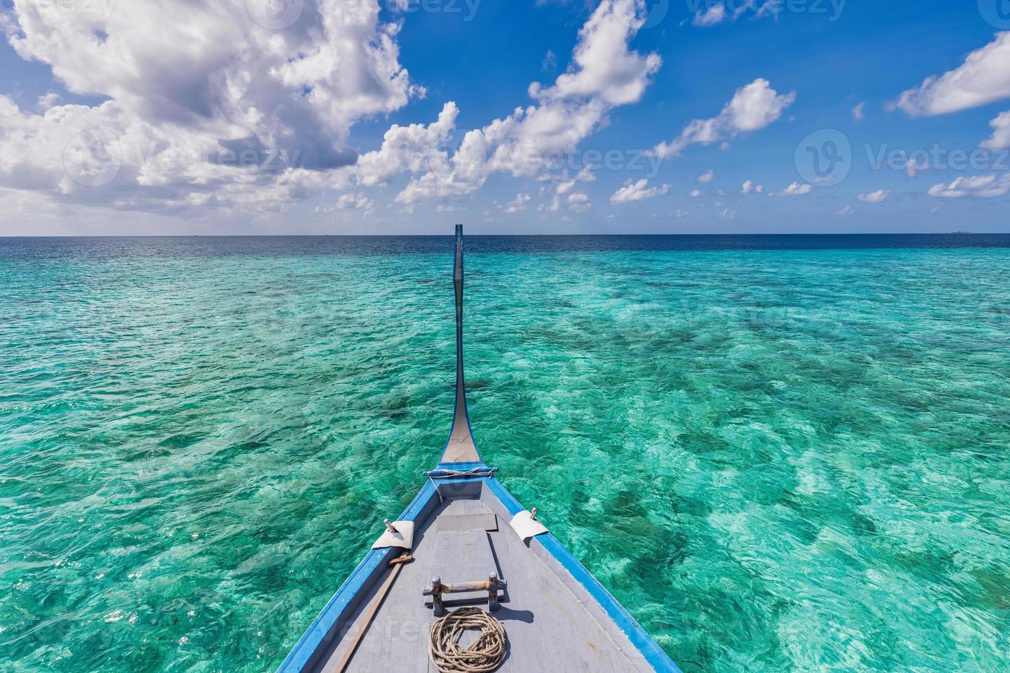 Boat in turquoise ocean water against blue sky with white clouds over tropical lagoon. Natural seascape landscape for summer vacation, panoramic view in Maldives islands. Dhoni boat, exotic travel photo