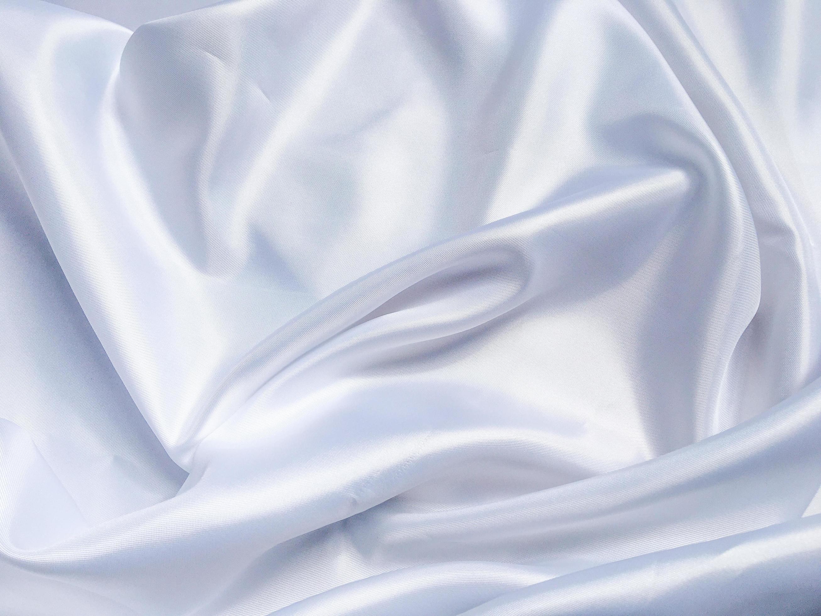 white crumpled fabric texture background. Silk curtain with fold waves